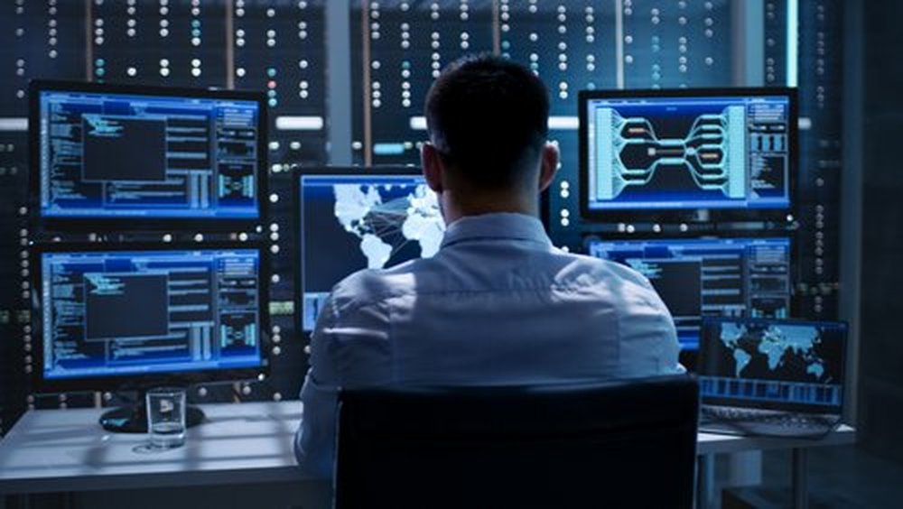 A cybersecurity specialist in front of a series of monitors