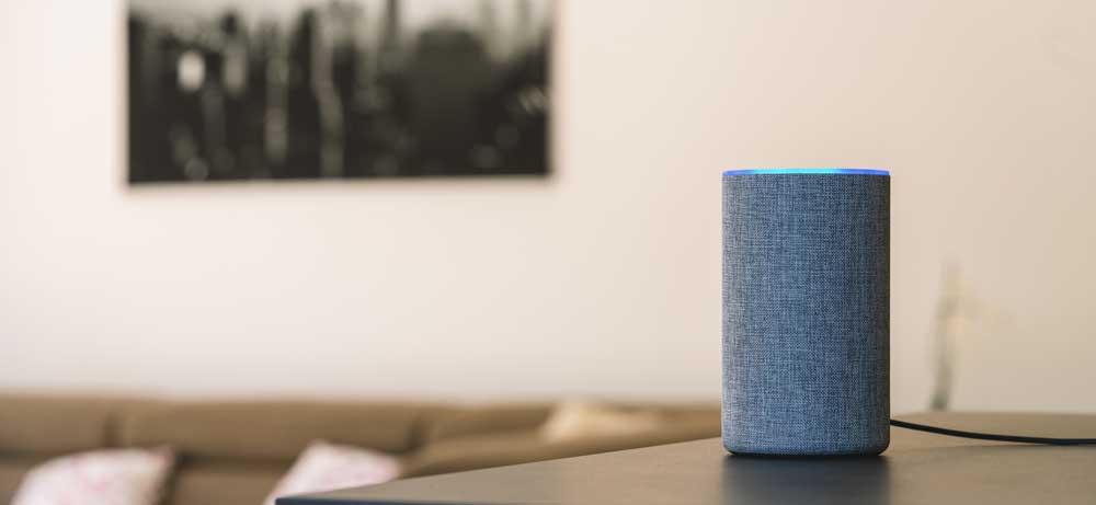 A voice activated speaker on a table. Smart home devices can present IoT security risks. 