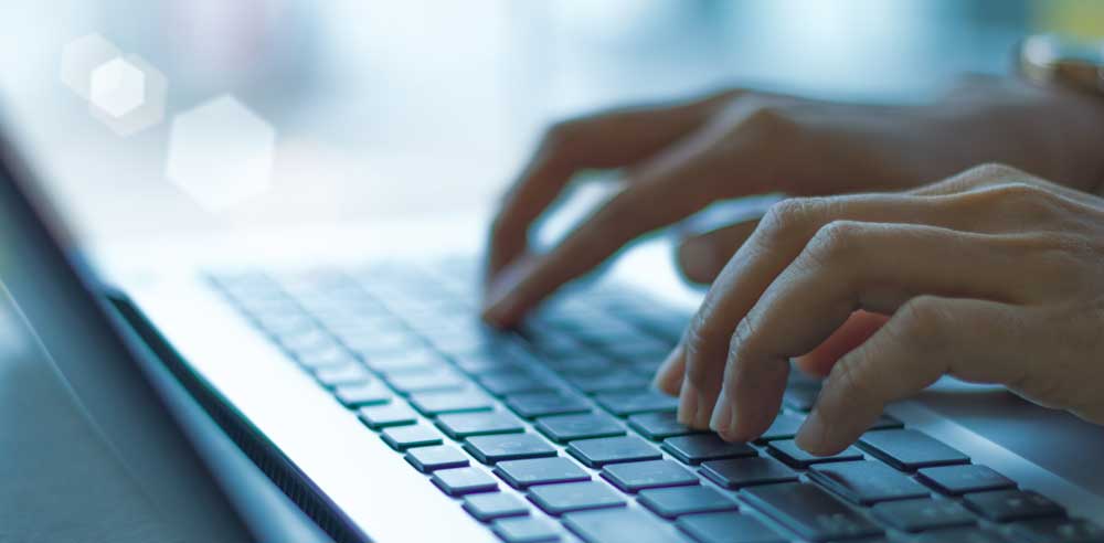 Closeup of a woman's hands typing on a laptop. 