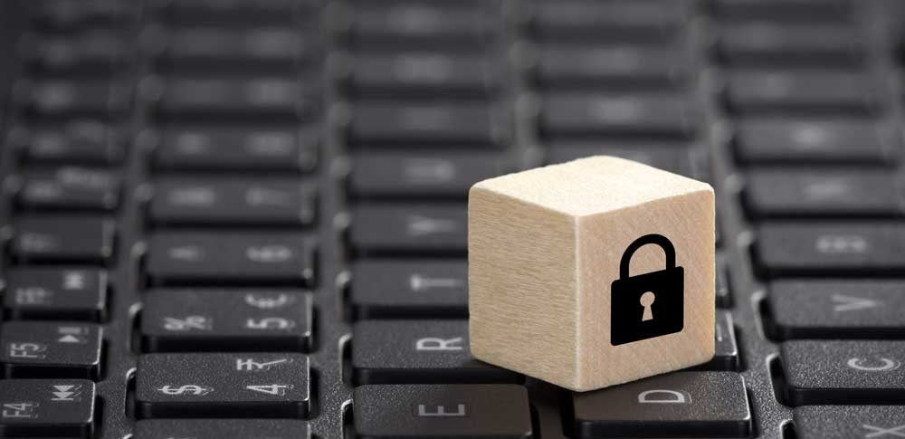 Small wooden block with a lock symbol on top of a keyboard. 