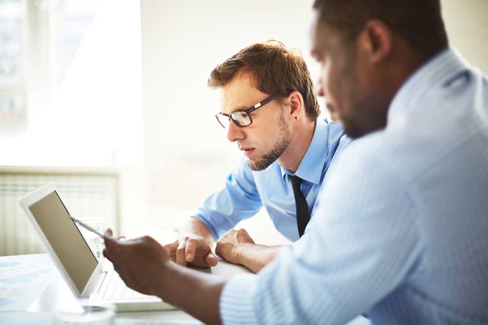 Manager talking with an employee in front of a laptop. 