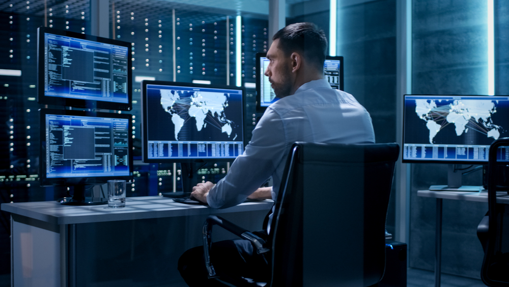 Cybersecurity analyst monitoring five different screens. 
