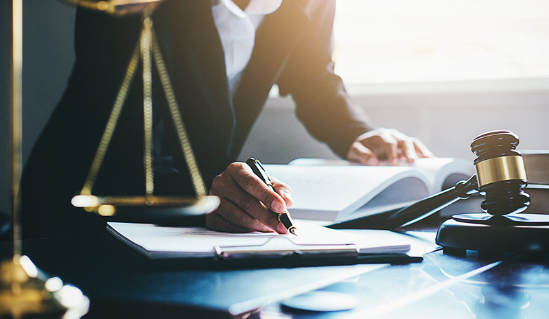 lawyer looking over a document with the scales of justice in the foreground. 