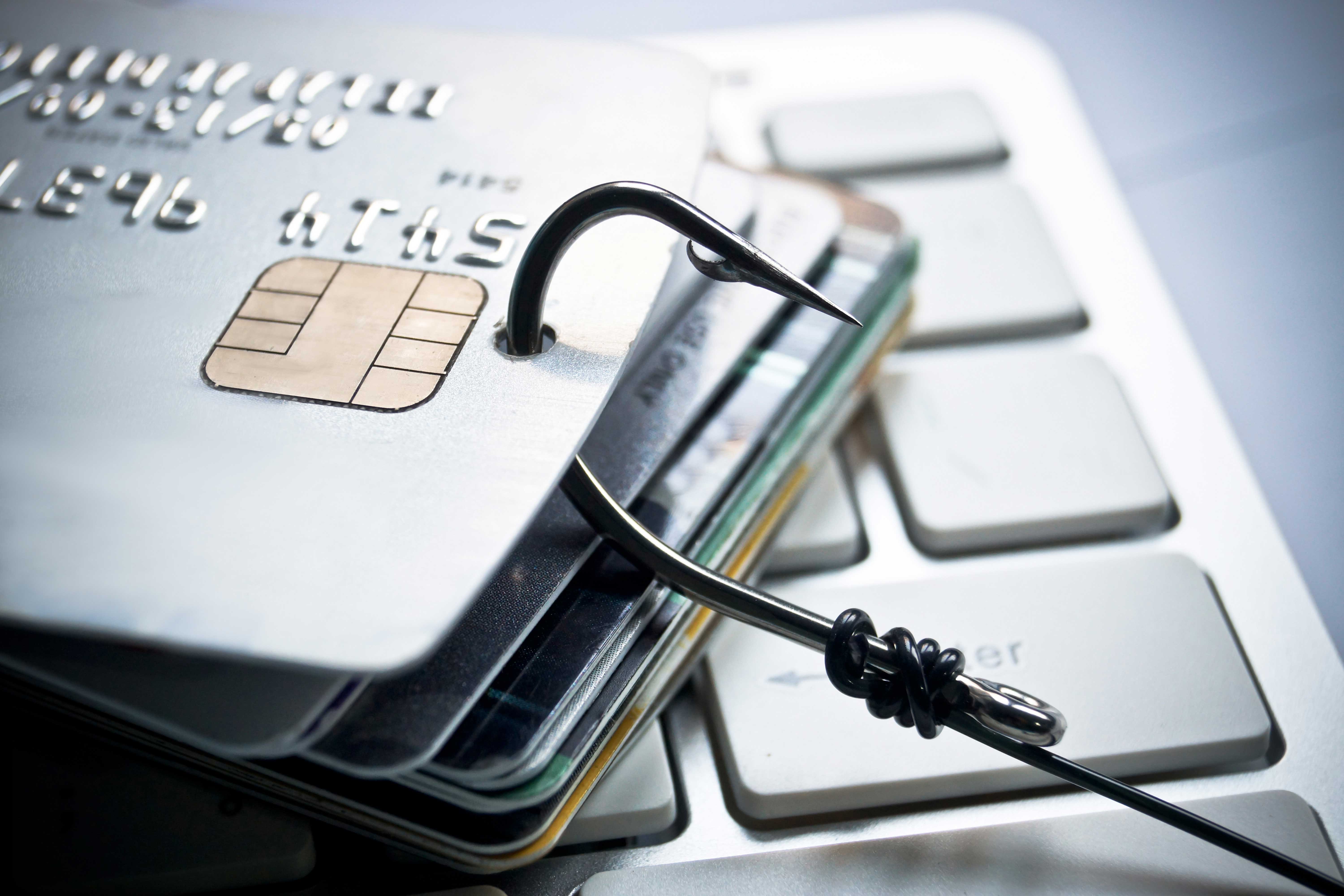 A stack of credit cards piled on top of each other with a fishing lure going through them. 