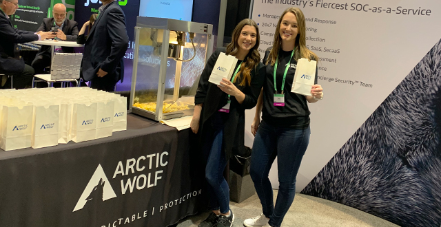 Two Arctic Wolf pack members holding up popcorn bags at our RSA 2020 booth. 