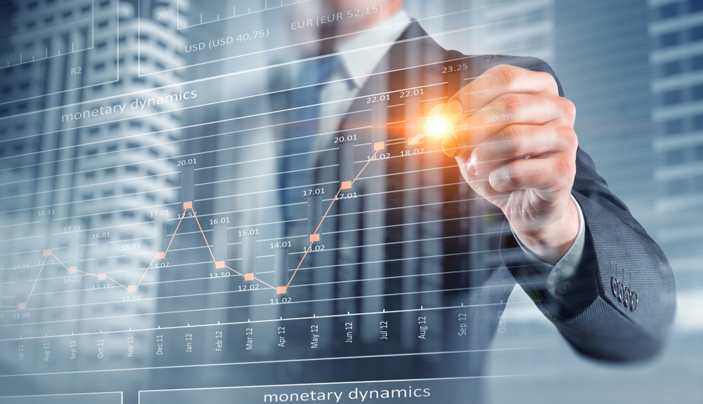 « Dynamique monétaire » écrit à l'écran ; un homme observe un graphique à barres 