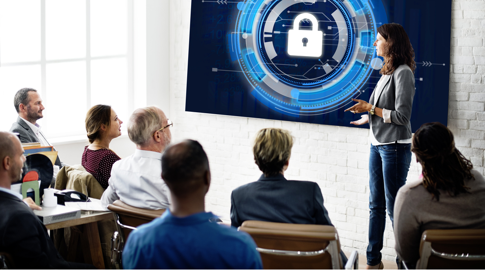 Security course class. Woman presenter is in front of a screen with a lock icon on it