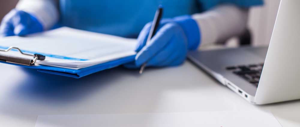 Closeup of a doctor's gloved hands holding a clipboard. 