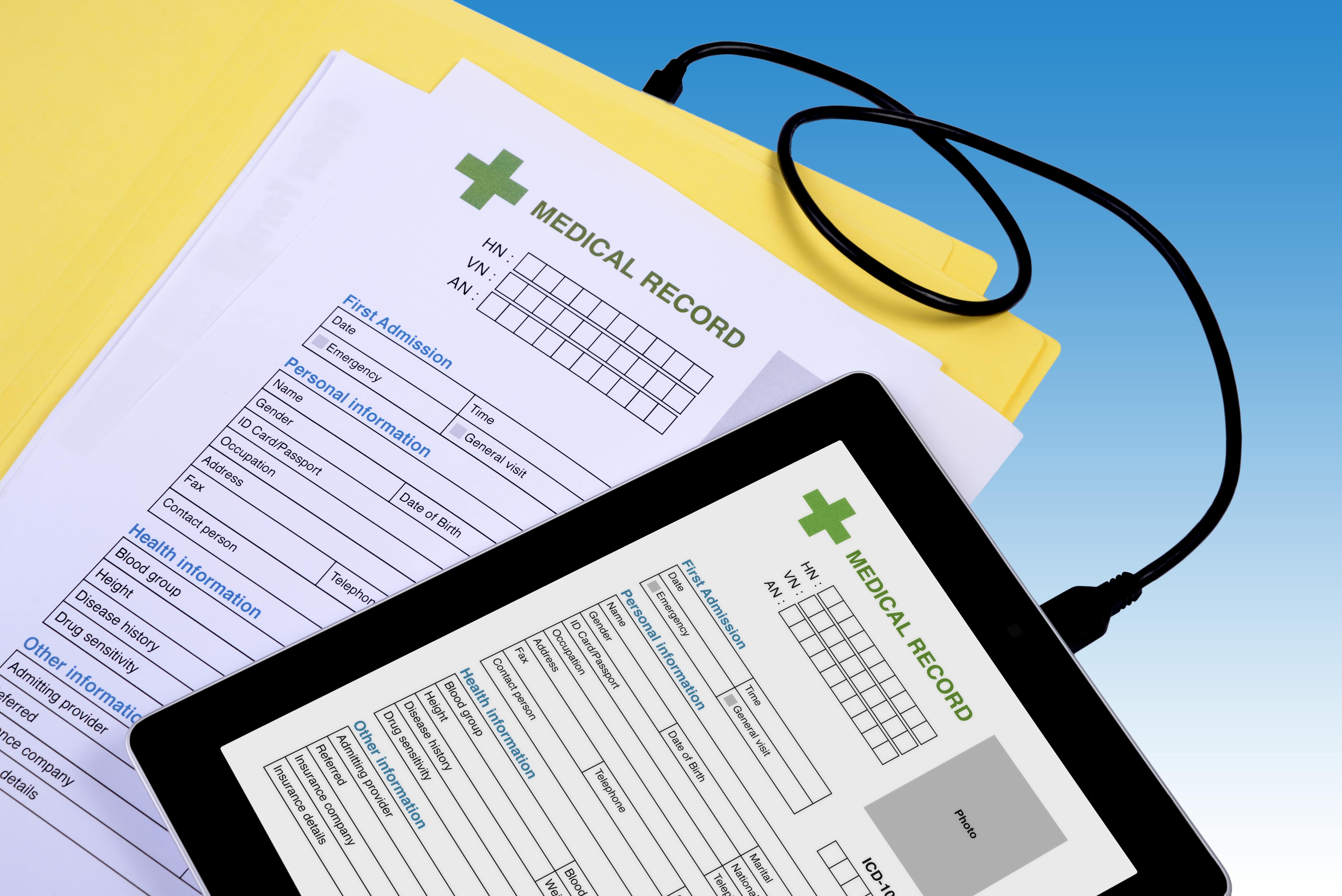 A tablet and clipboard with medical record information on them. 
