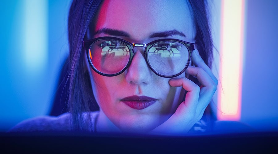 Technician looking at laptop, laptop screen reflecting in glasses