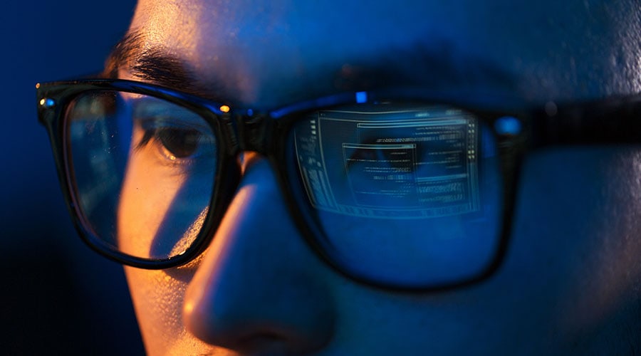 Person wearing glasses reflecting computer screen