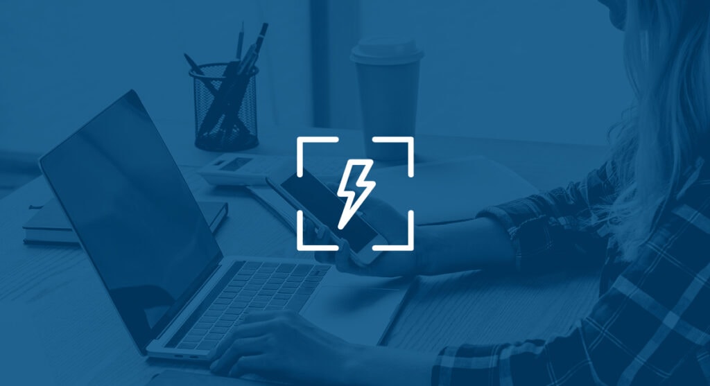 Laptop on a desk with a lightening symbol on the screen.