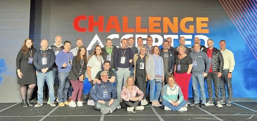 The Arctic Wolf UK team in front of a Challenge Accepted sign. 